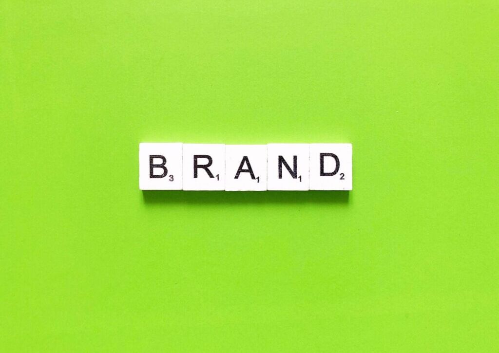 Scrabble tiles spelling "BRAND" on a vibrant green background, representing a branding agency in London.