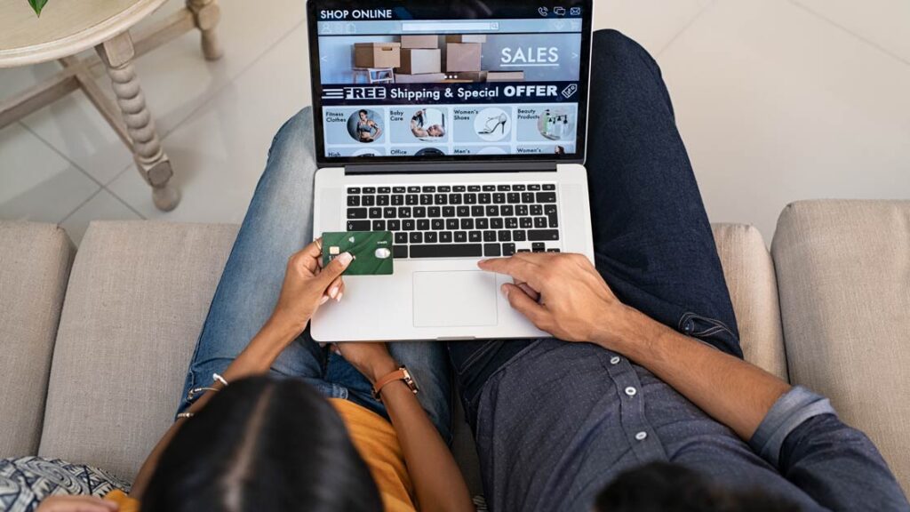 Couple shopping online deals on laptop for Budget Ecommerce Web Design in London, with card in hand.