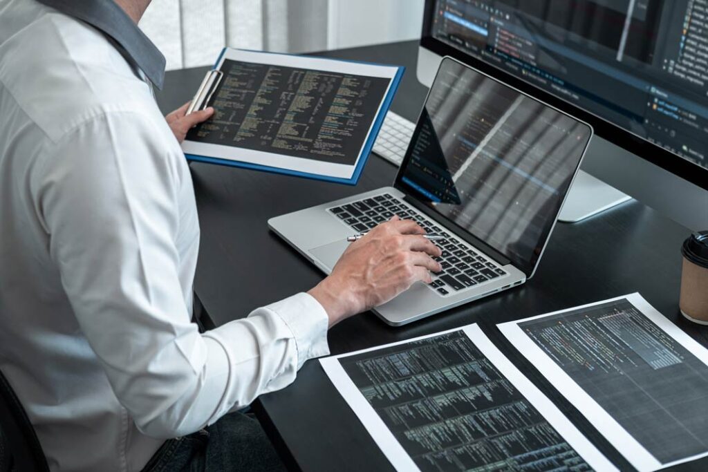 Developer working on Custom Drupal Development in London with code displayed on laptop and monitor.