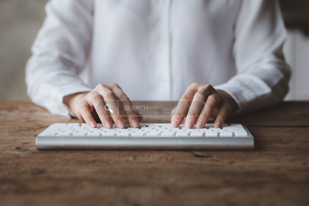 Hands typing on a keyboard with a search bar overlay. Cost-effective SEO agency services in London.