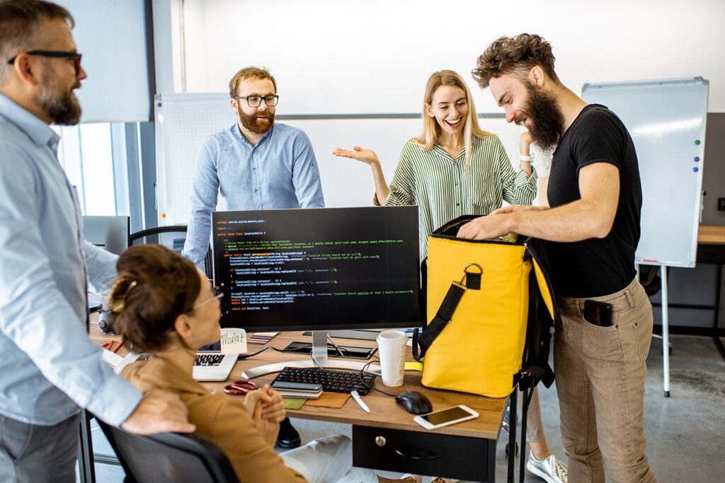 Team at best mobile app development company in London collaborating around computers and coding in a modern office.