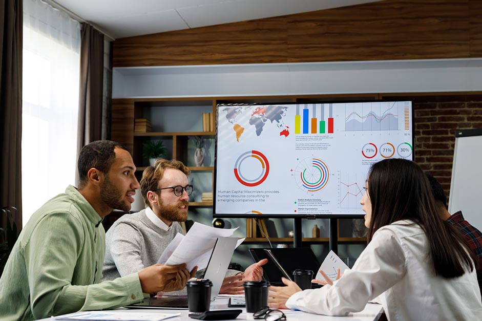 Team discusses Top Six Data and Analytic Trends for 2024, with charts displayed on a screen in a modern office.