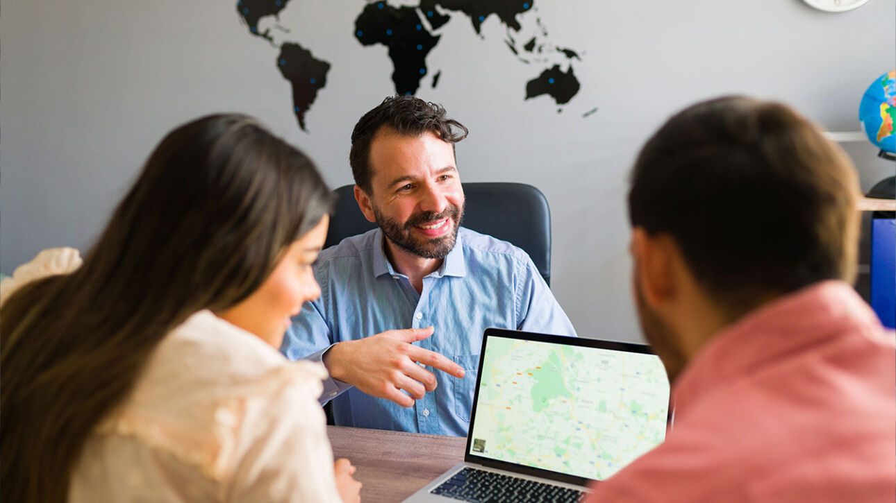 People discussing digital marketing strategies in London office with world map on wall and laptop on table.