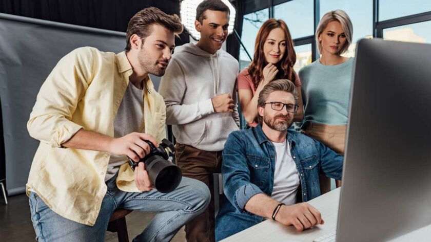 A team discusses SEO strategies around a computer, representing The Right SEO Service Provider in London.