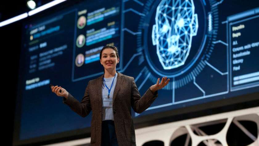 Speaker presenting on stage about the cost to build an app like Character AI, with digital face visualization.