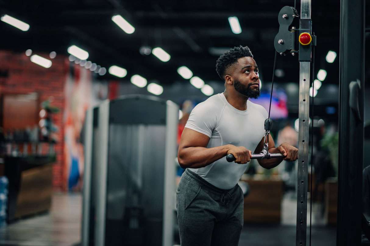 Man exercising on cable machine in gym, highlighting SEO for gyms by showcasing a workout environment.